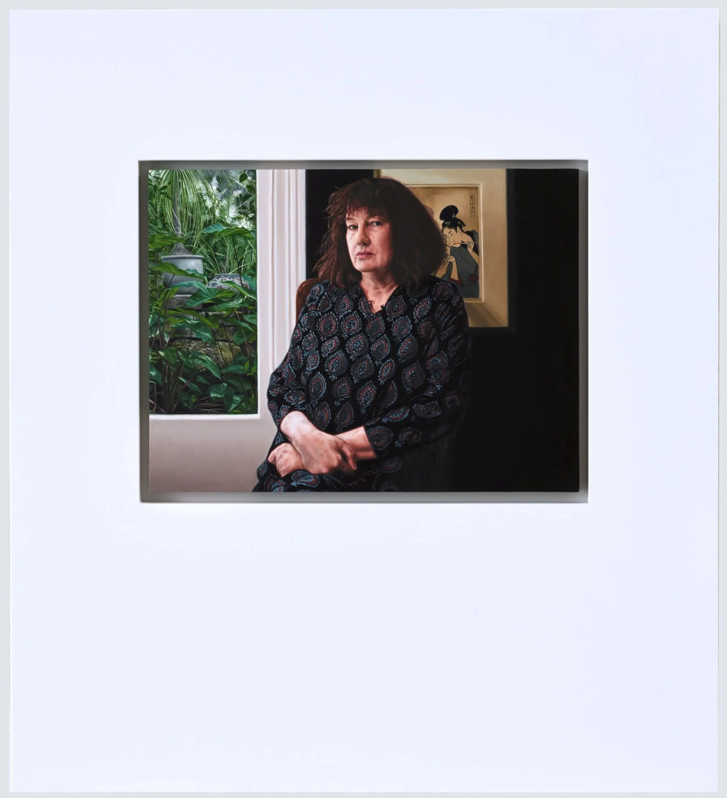 A painting of a woman with brown curly hair, sitting inside in front a window looking onto a gardenand a framed painting