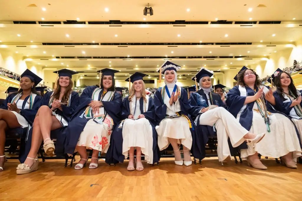 A group of graduates sitting during their graduation ceremony in their caps and gowns