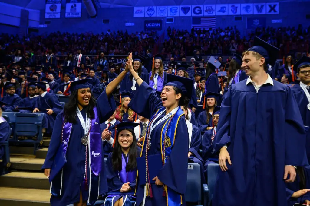 Students in their caps and gowns high-fiving
