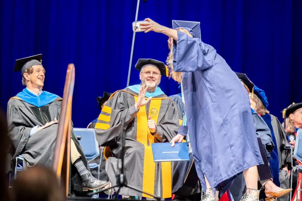 Graduate taking a selfie with a delegate on the graduation stage