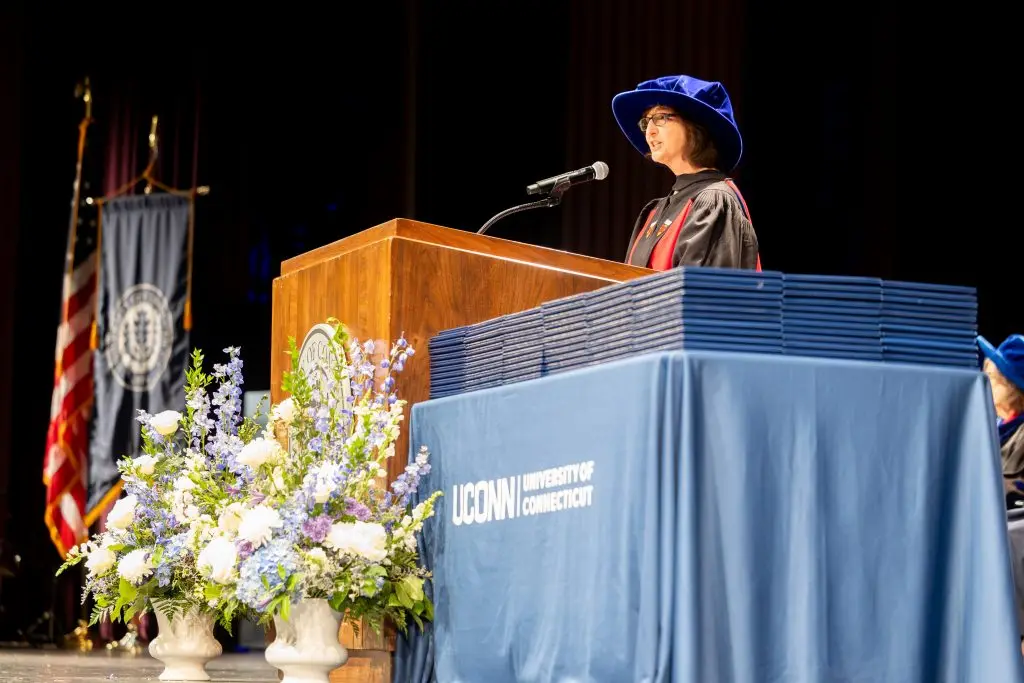 A speaker at the podium next to a table of diplomas