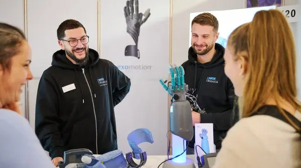 A group of people stand around a mechanical hand