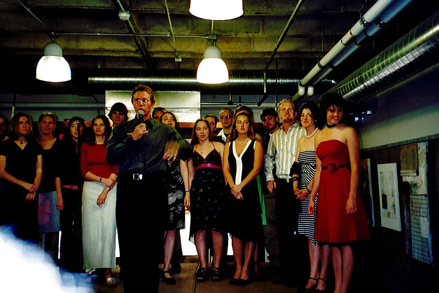 Wendell Arneson makes remarks at the 2004 Senior Art Show opening reception, with the class of 2004 studio art majors in the background.