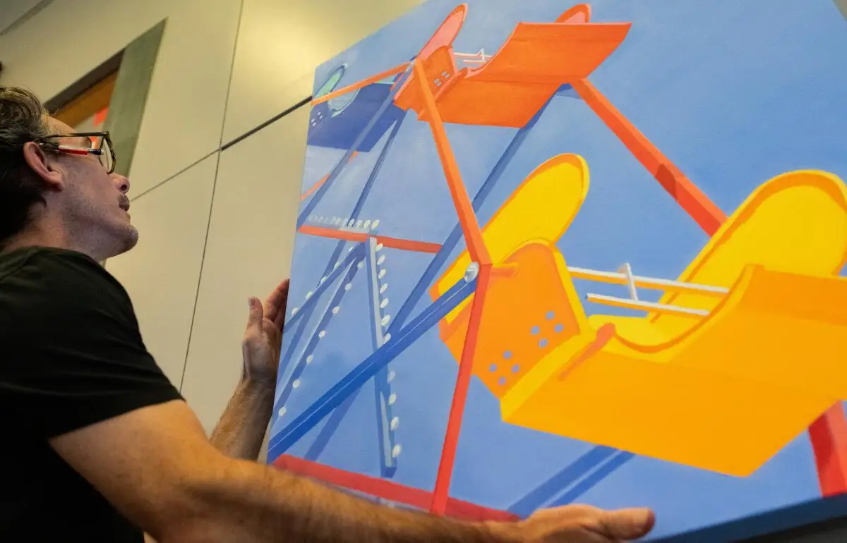 Josh Hoyer installs a painting at the Newport Beach Central Library of the Balboa Fun Zone's Ferris wheel.