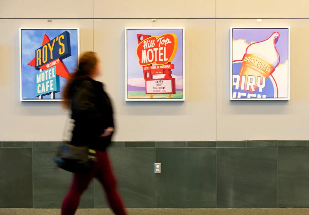 A library visitor walks past paintings by artist Joan Gladstone.