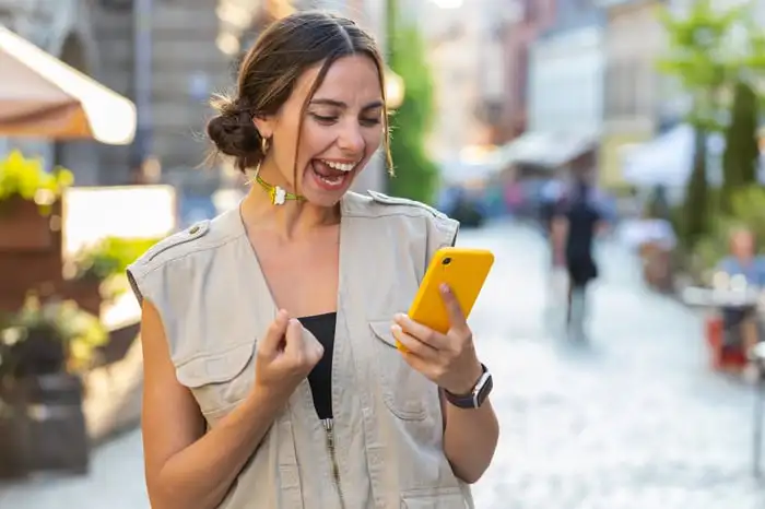 Person reacting joyfully to something on a smartphone.