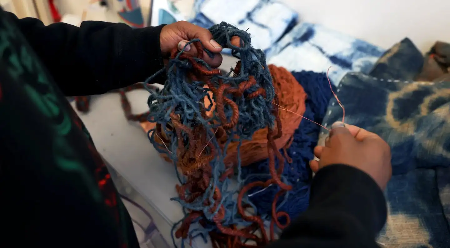 Stephen Hamilton sorts through yarn he dyed with natural pigments in his Allston studio.