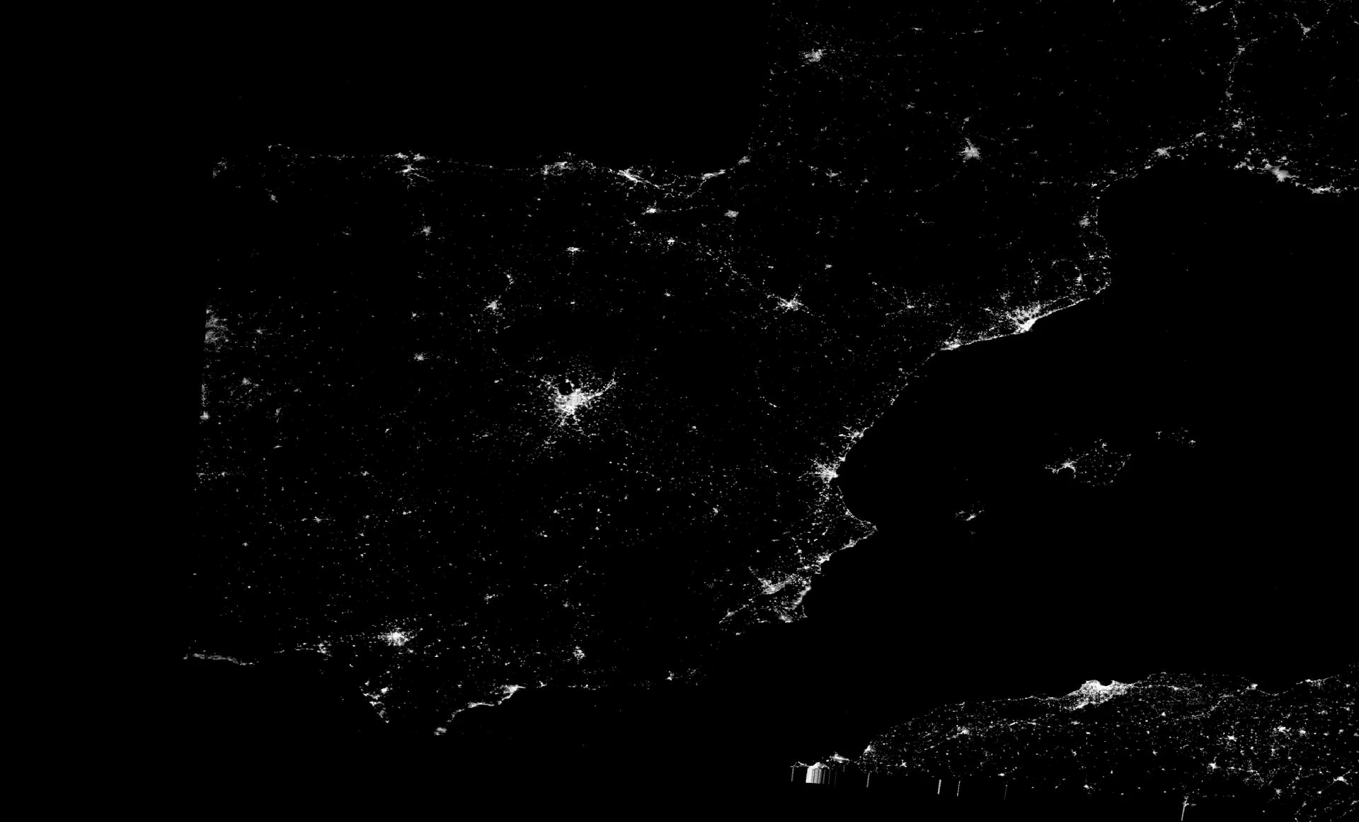 a satellite view of a country at night, dotted with city lights, but containing a dark area where a power blackout occurred