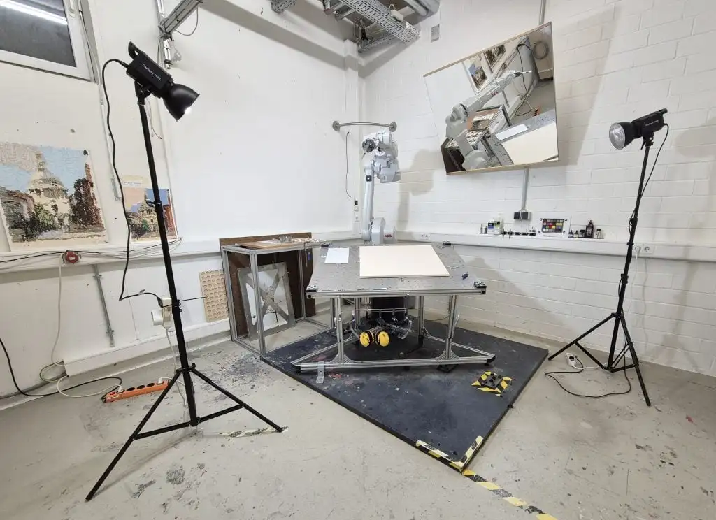 studio set up with a robot and cameras and a canvas on the table