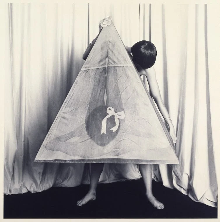Chadwick holding a large photo of herself posed in a shape that looks like a vulva