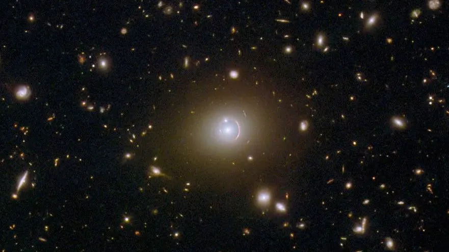 a black background speckled with bright points of light and small arcs, each being a distant galaxy