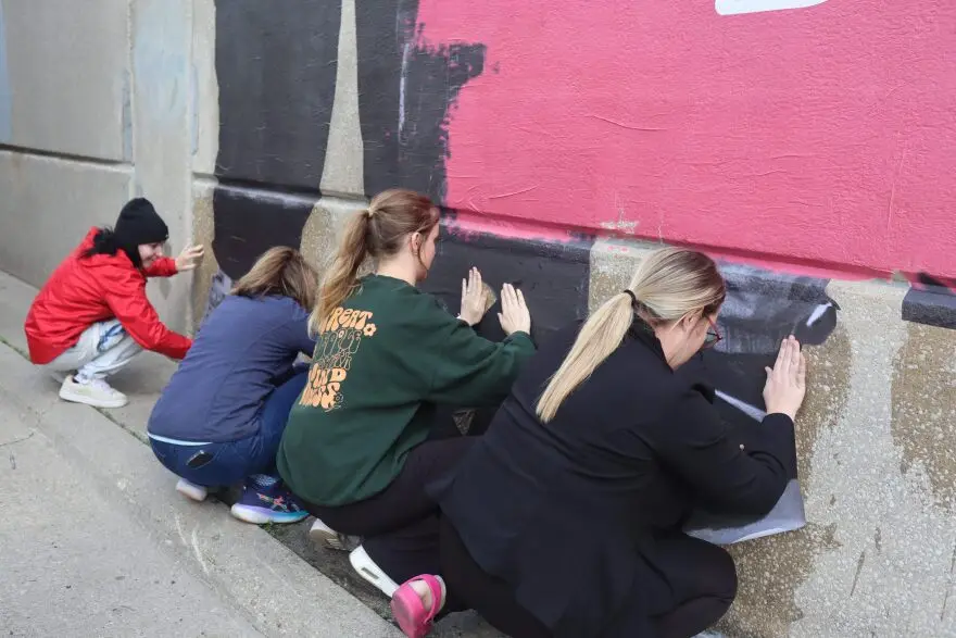 Volunteers press panels of the mural, Diversity is Our Strength, onto the wall of a parking ramp in downtown Waterloo.
