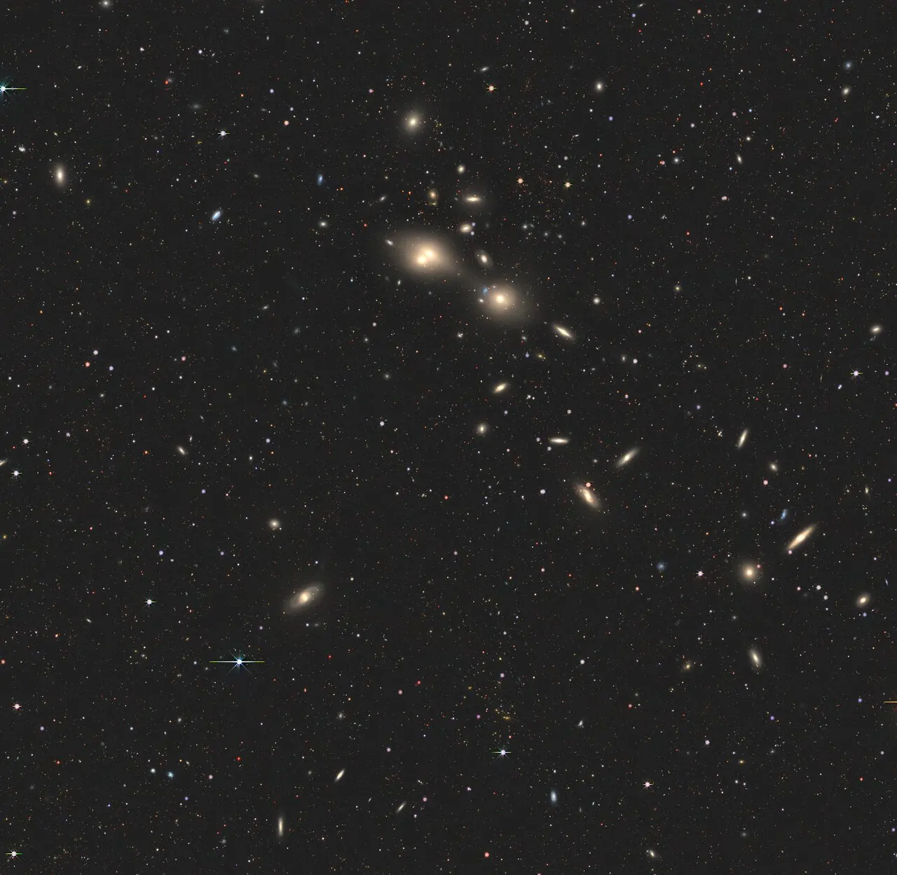 A view of a section of space with lots of bright dots. Very bright dots, about two, in the center.