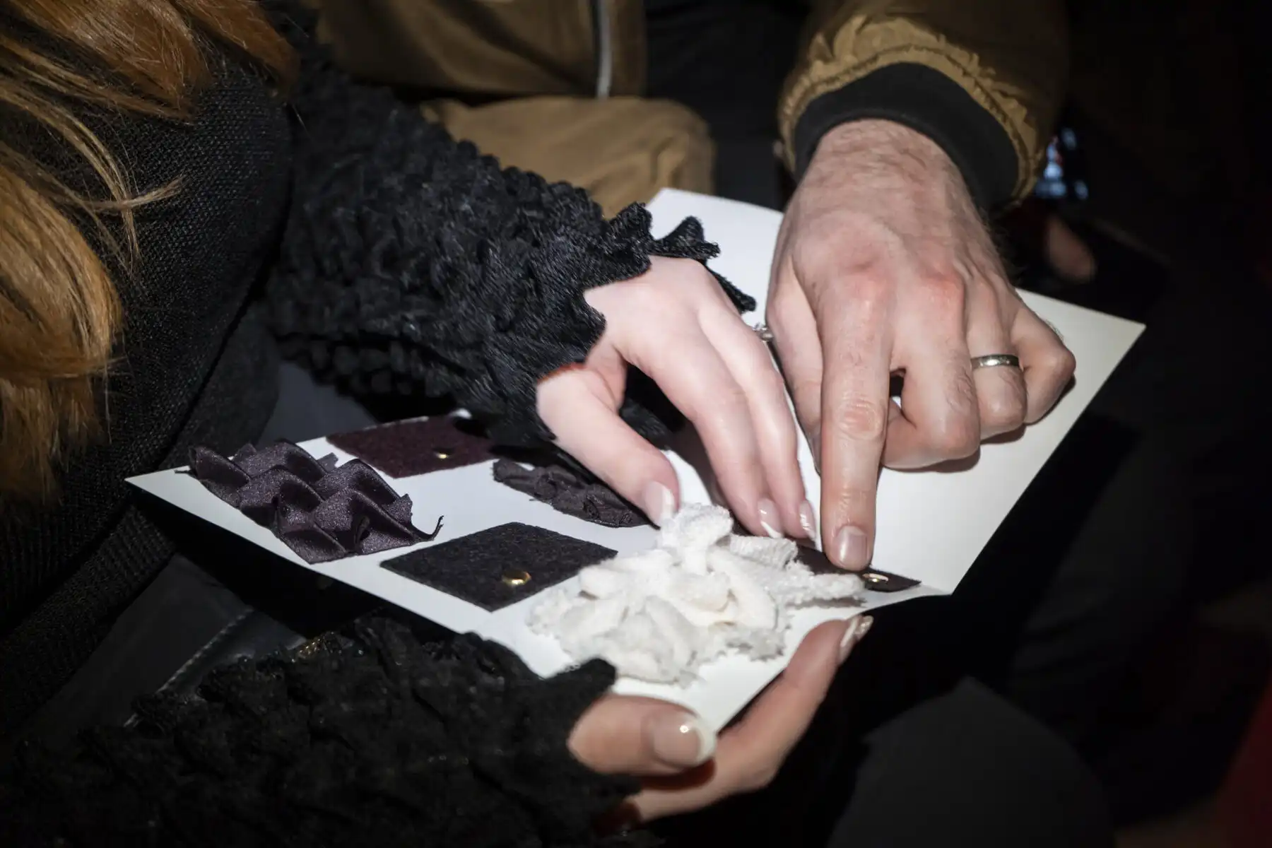 Hands of blind people touching fabric swatches.