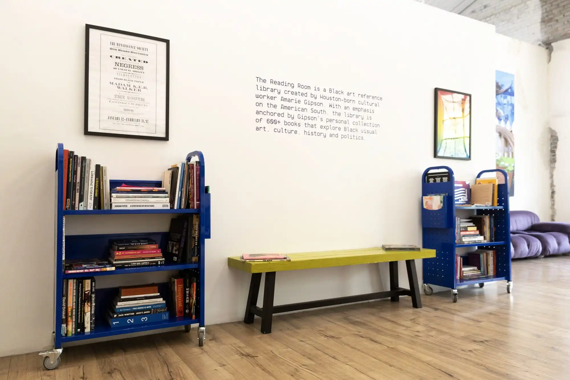two blue library carts with books and a bench in between them