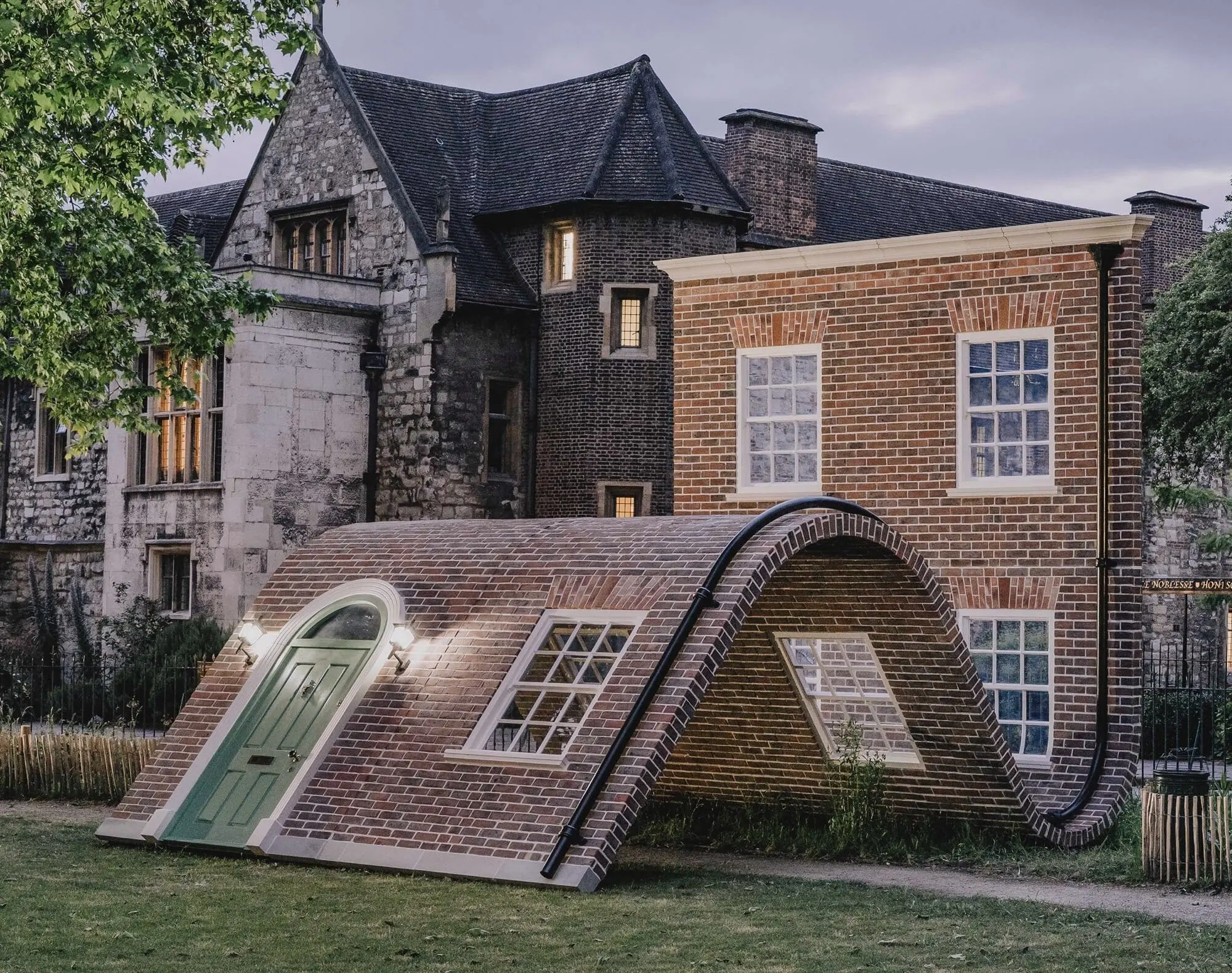 a public art piece in a a park featuring the facade of a London townhouse that appears to sit on the ground with its knees up