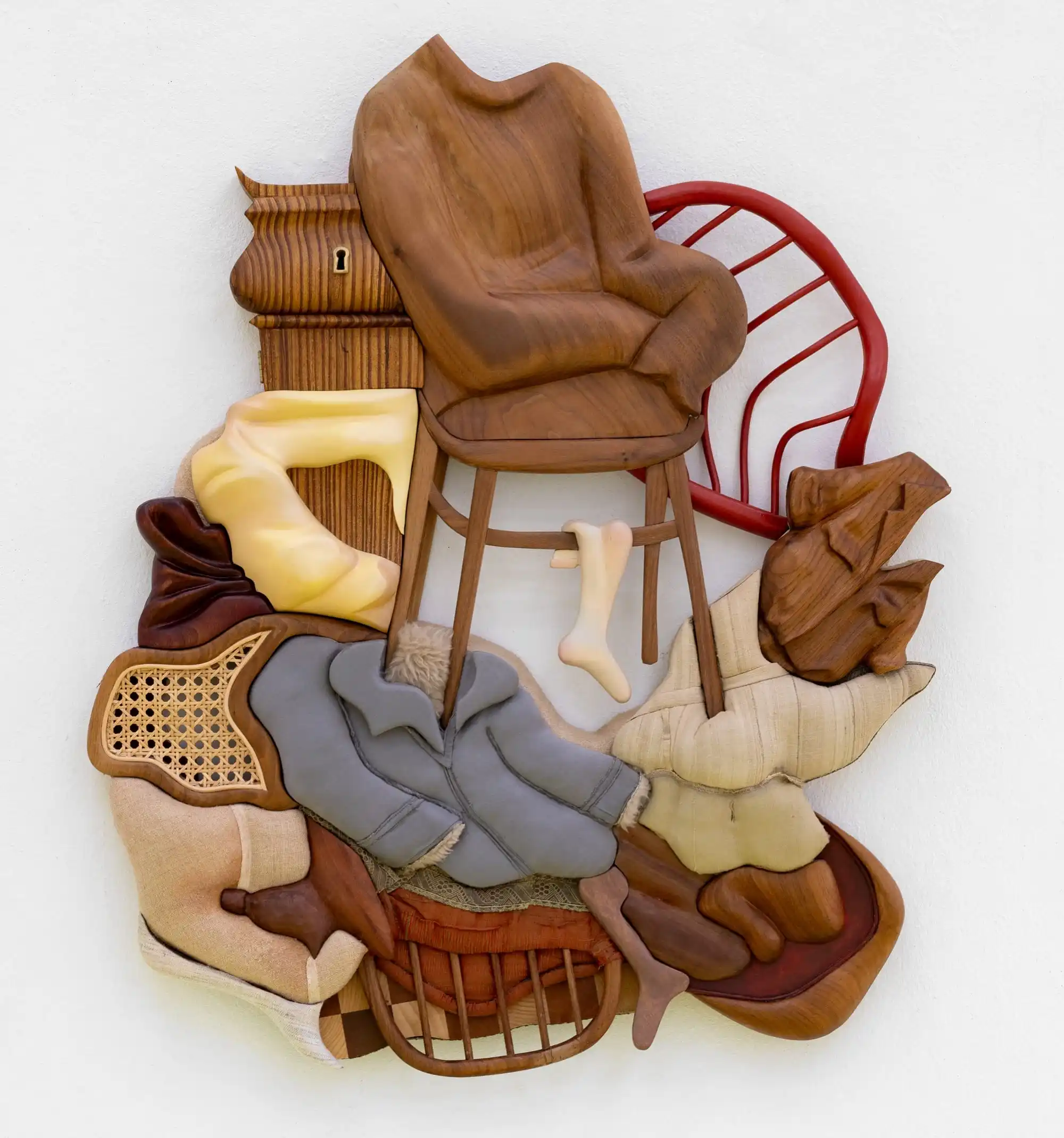 a mixed-media abstract wall sculpture with furniture and clothing forms