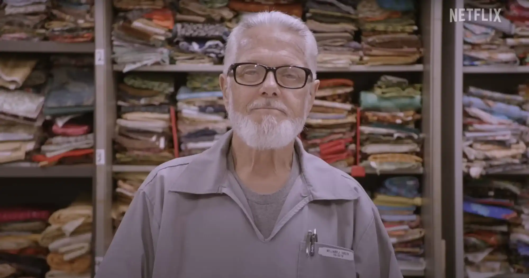 a man standing in front of shelves of fabric
