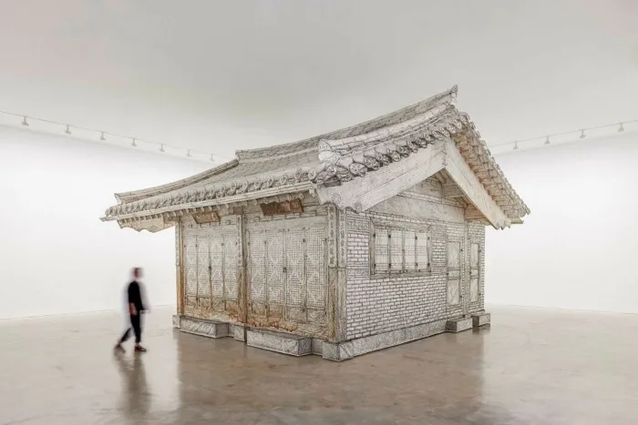 A sculpture of a traditional Korean house made from graphite-rubbed paper
