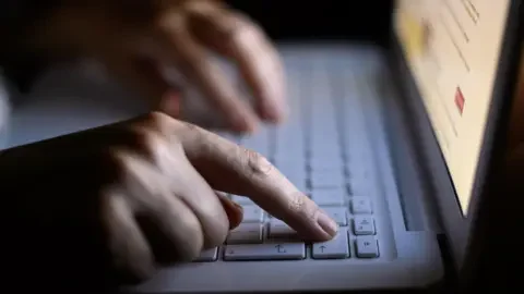 PA Media A person types on a laptop.
