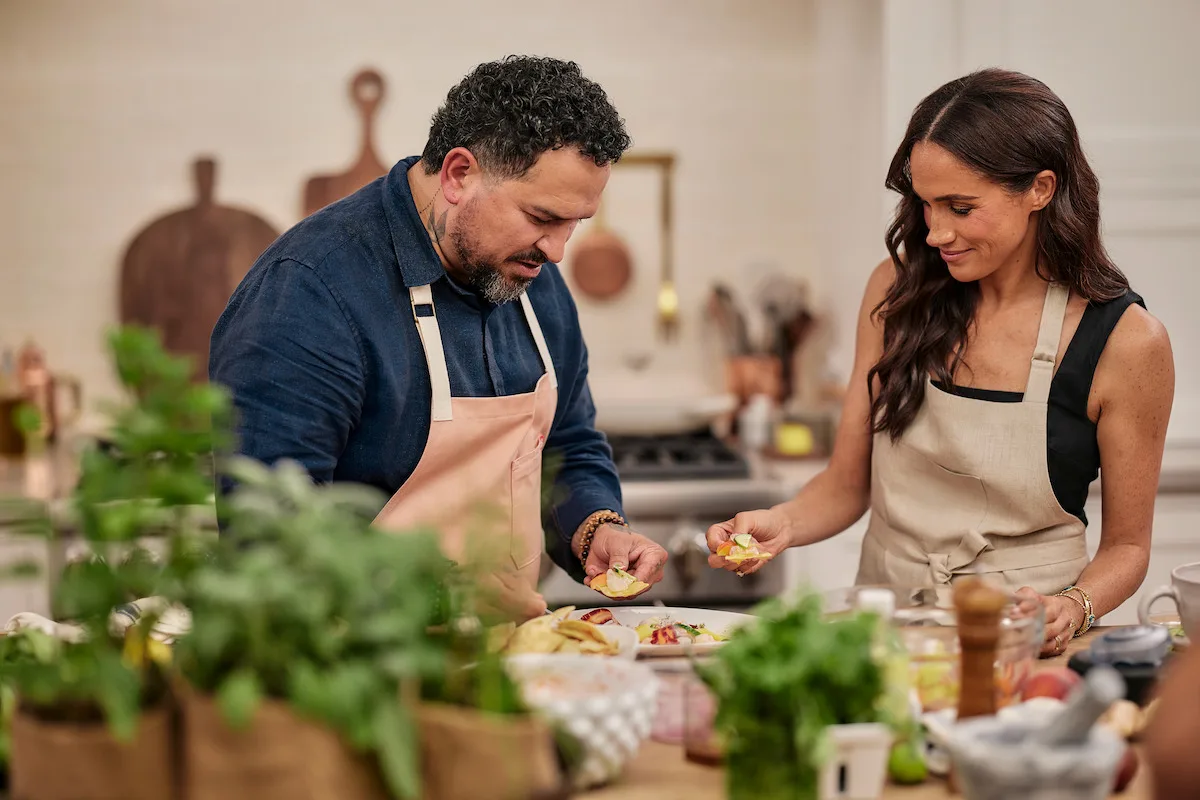 Ramon Velazquez and Meghan tasting food in the kitchen.