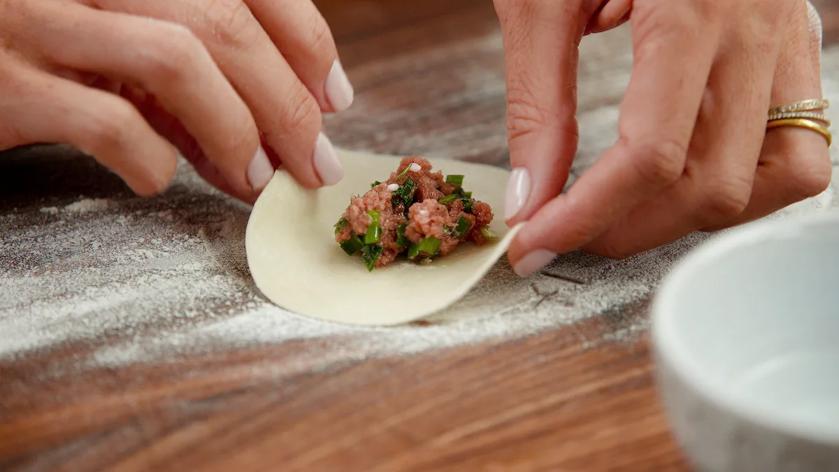 Potsticker filling being put into a dumpling wrapper.