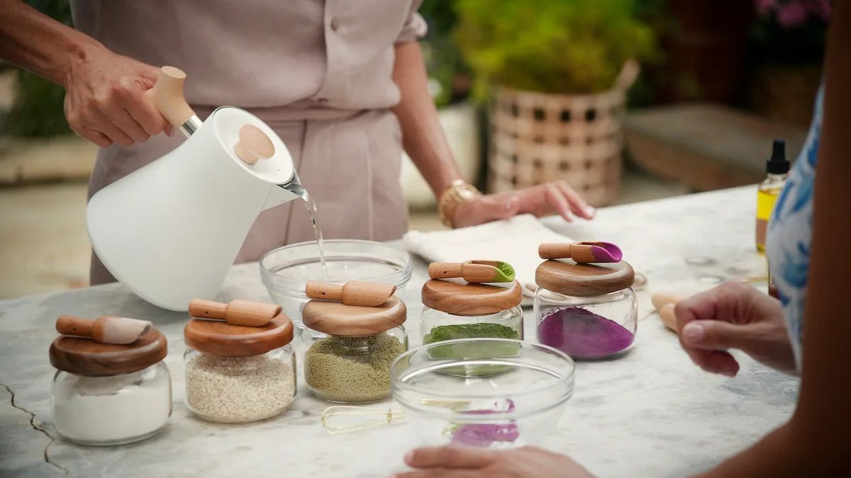Hot water being poured into a bowl with several powders placed in front of it.
