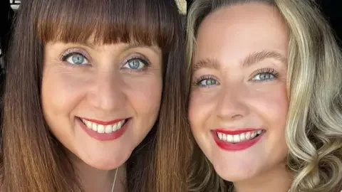 Jessica Morgan-Helliwell Jessica (on the right with curled blonde hair) and her mother Louise (on the left with long brown hair and a fringe) are smiling in a selfie. 