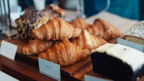 Getty Images Croissants and cakes lined up in a bakery window 