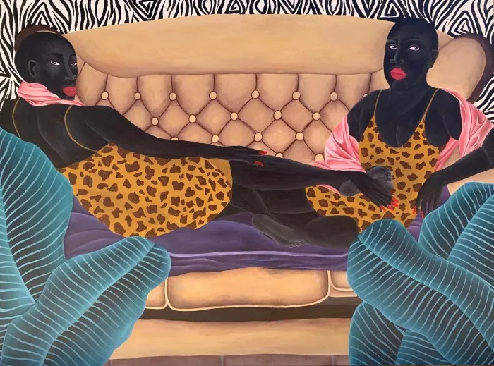 A painting of two women in vivid print dresses sitting at either end of a buttoned sofa; one woman has her feet resting on the other woman’s knees