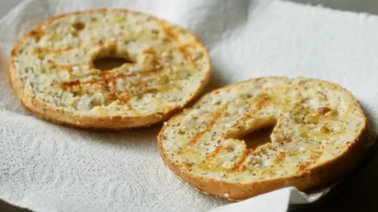 Two toasted bagel halves on a paper towel
