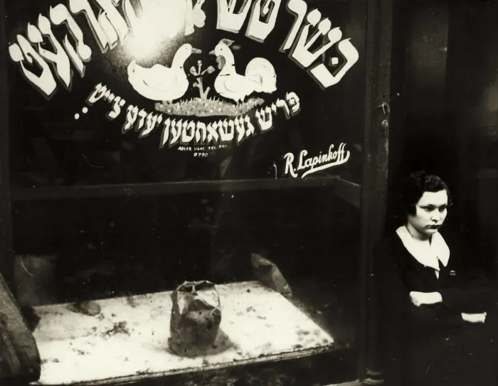 A photograph from the 1930s shows a glum-looking woman standing outside a kosher butcher’s shop with a lump of unidentifiable meat in the window