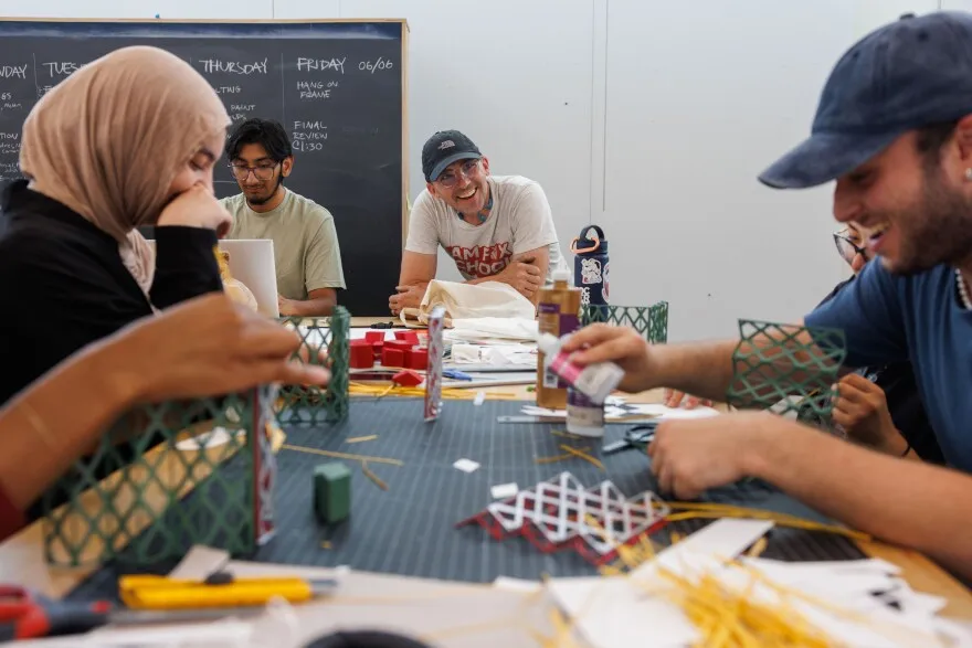Project manager Greg Cuddihee laughs with architecture students in the Sam Fox School of Design & Visual Arts while the group works on constructing prototypes of a pavilion they will be building for the Hyde Park Farmers Market June 3, 2025 at Washington University in St. Louis, Missouri.