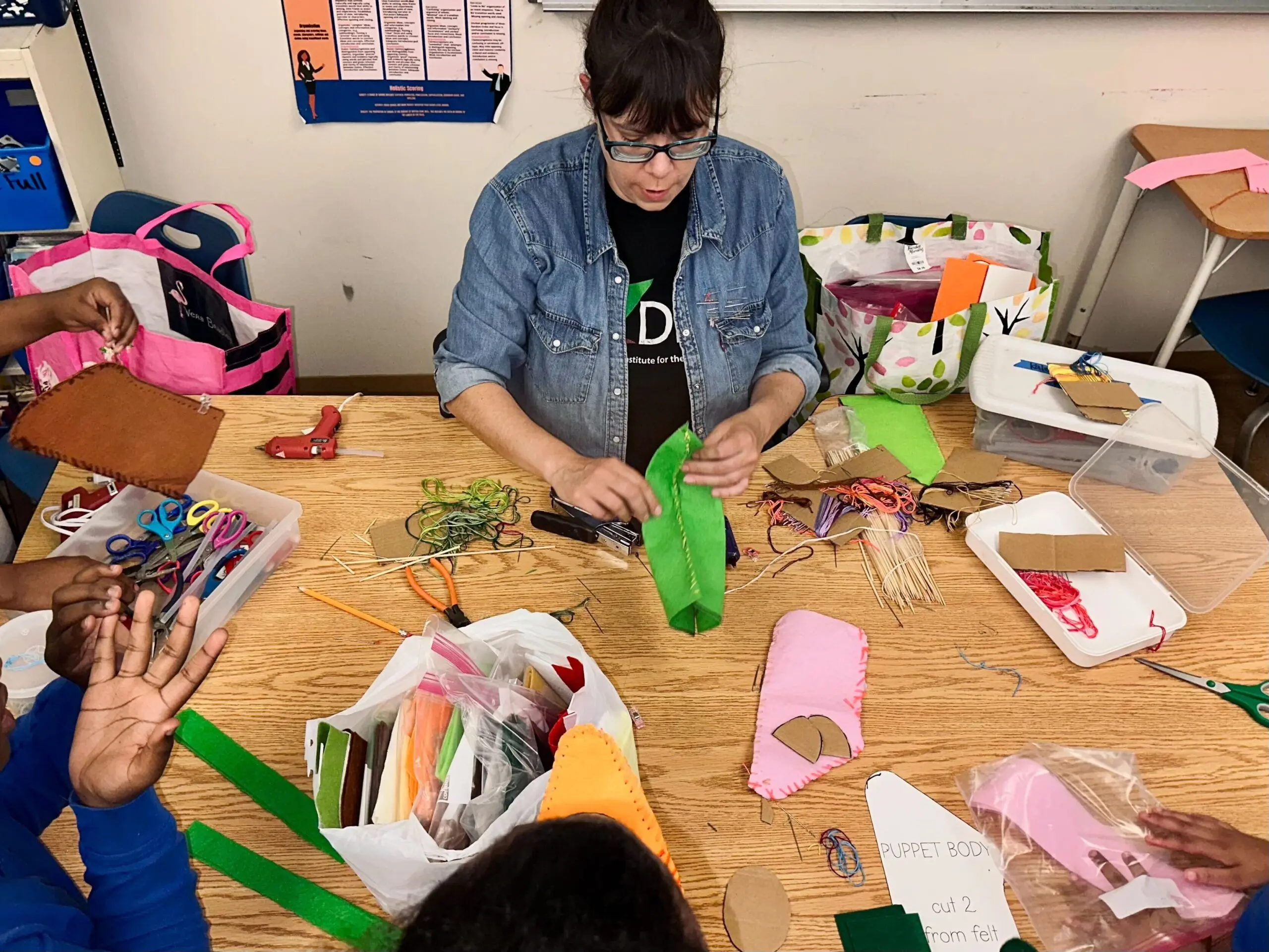 Kate Testa helps three students with puppets