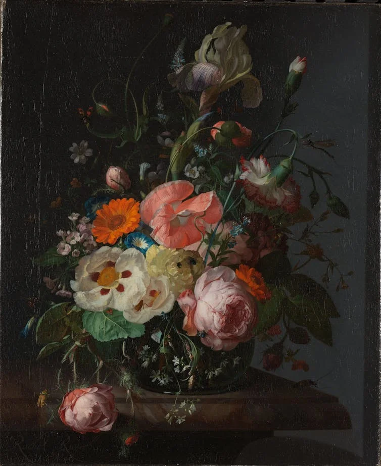 Still life of many flowers against black background, with insects landed on some leaves.
