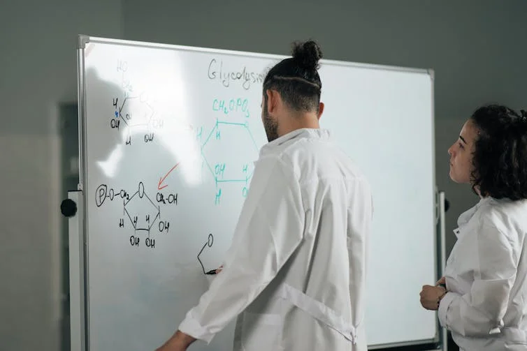 Man and woman at whiteboard with chemistry drawings