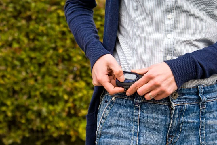 A woman checks a pedometer on her hip.