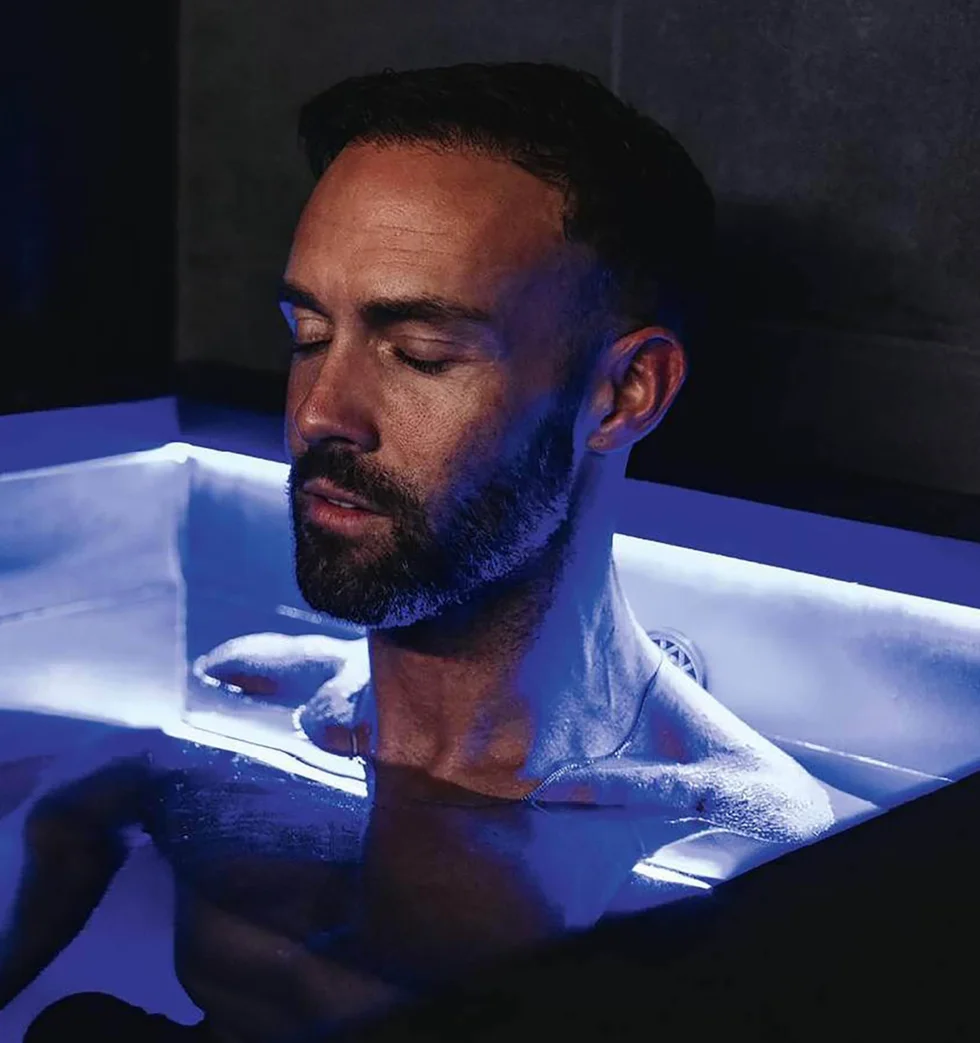 person relaxing in a modern bathtub with blue lighting