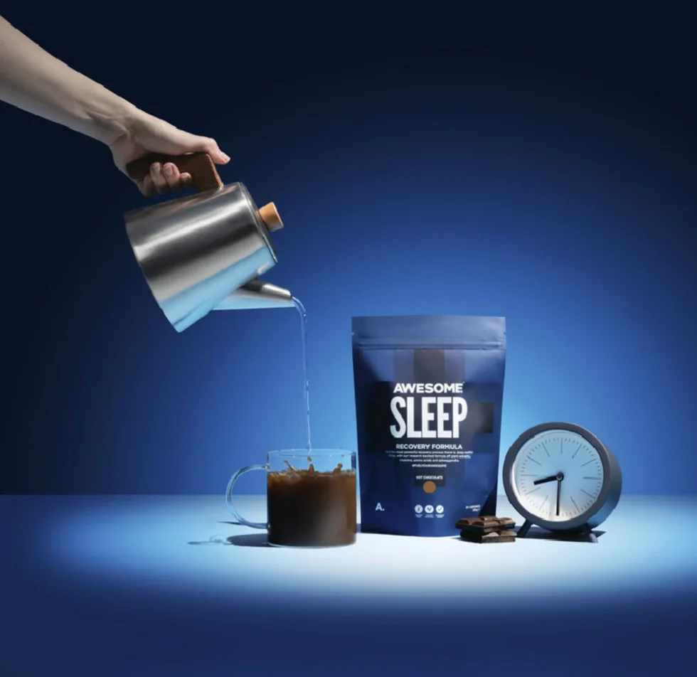 a hand pouring water into a glass mug next to a sleep aid product and a clock