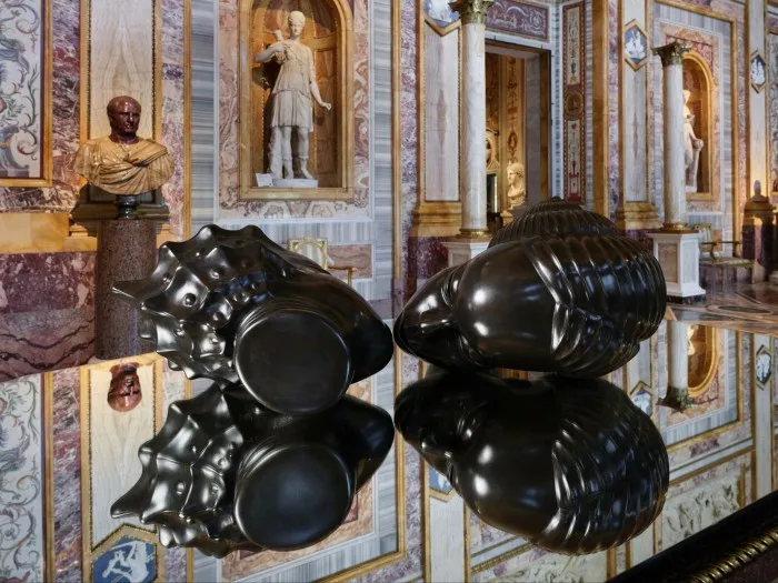 Two bronze heads lying on a mirror