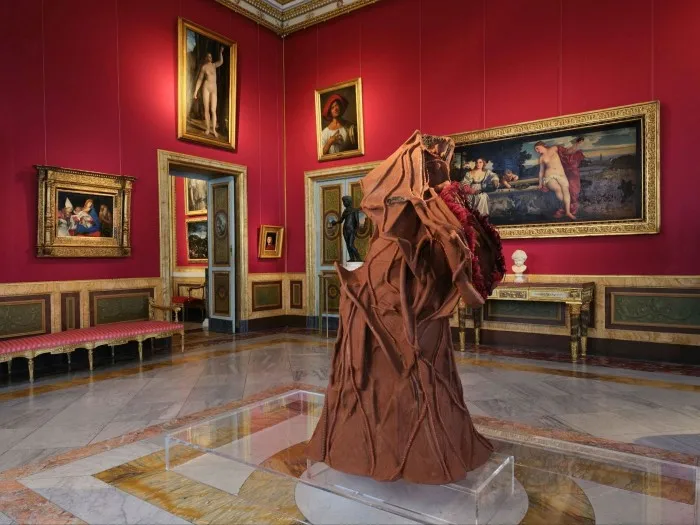 A brown sculpture with red detail in the centre of a red room