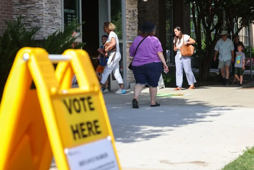 People walk out of the poling center at the John and Judy Gay Public Library in McKinney,...