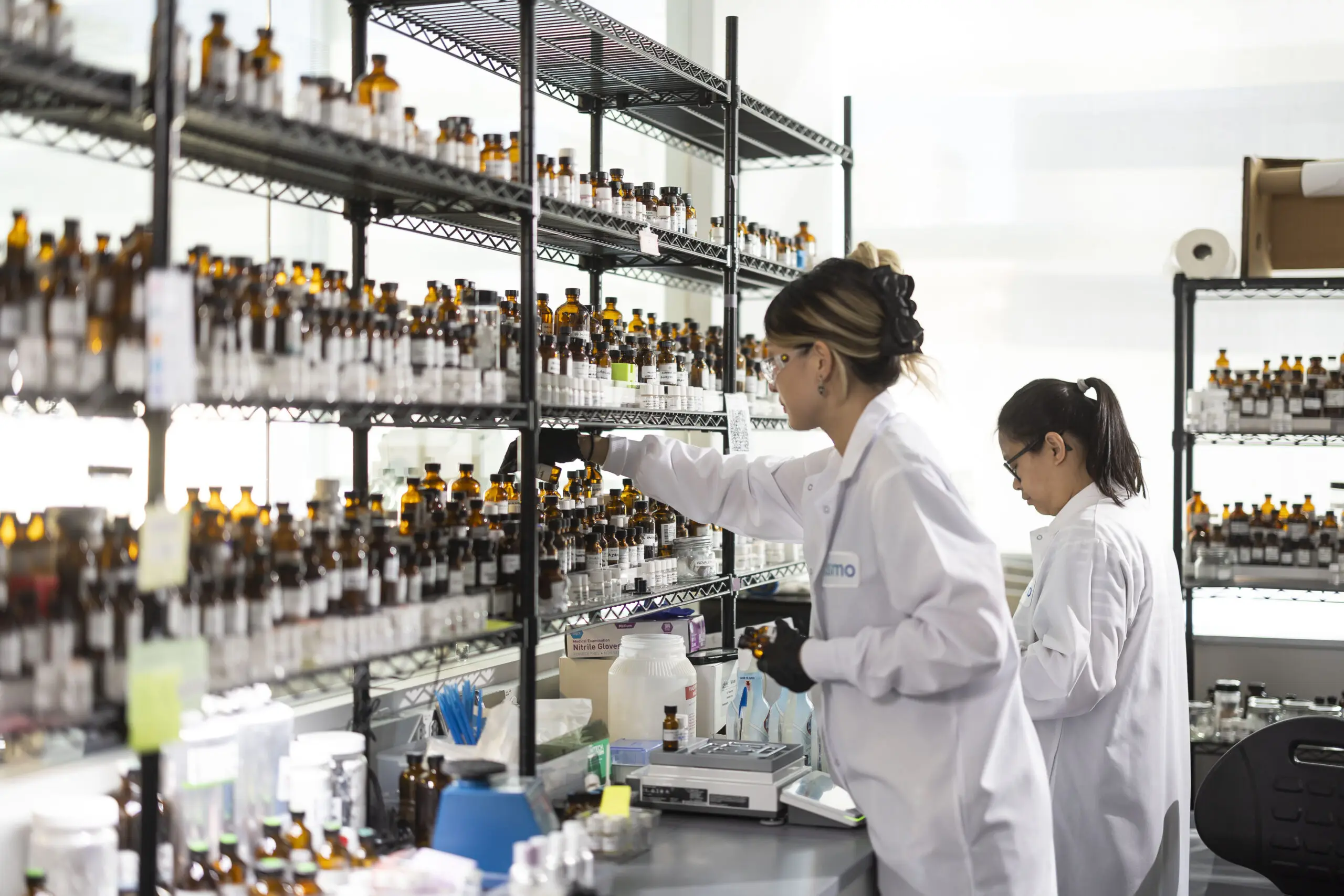 Perfumers in lab coats in a lab full of vials