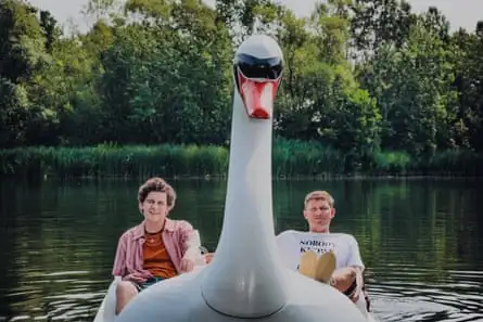 Two white young men reclining on a swan pedalo.