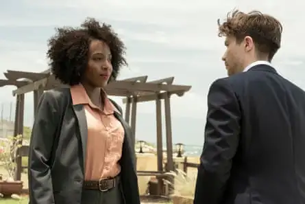 A black woman in a smart blouse and overcoat is looking at a white man in a suit