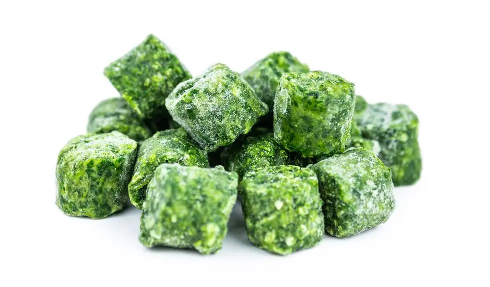 healthy frozen foods: chunks of frozen spinach isolated on white background