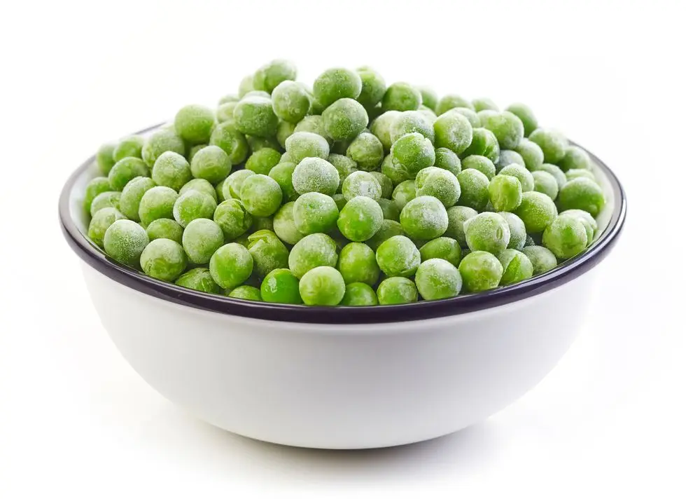 healthy frozen foods: bowl of frozen green peas isolated on white background