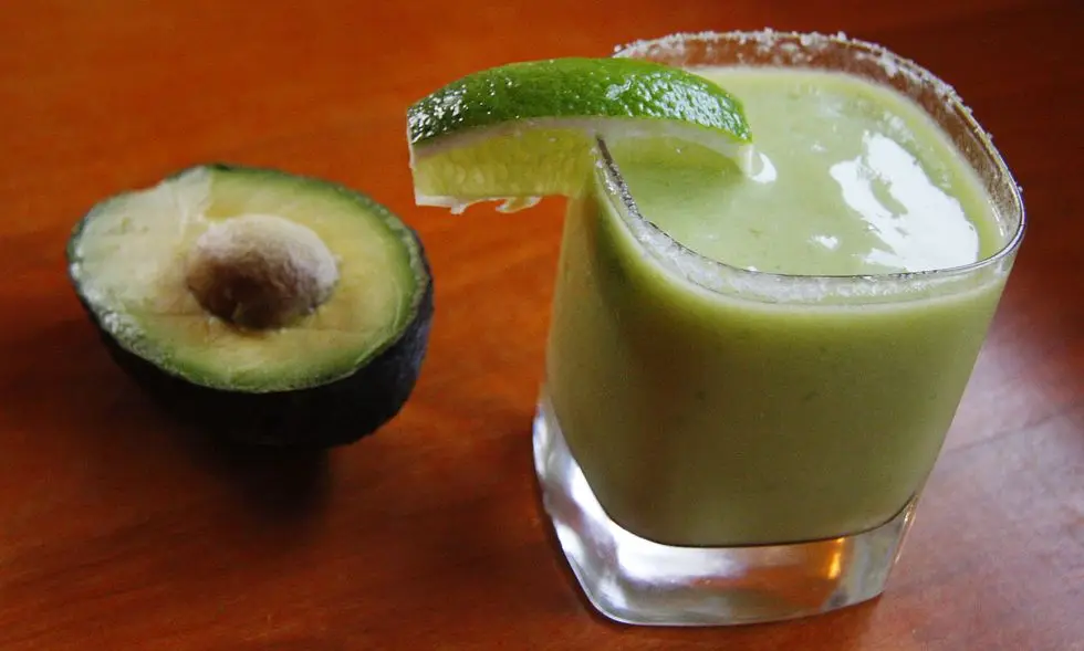 healthy frozen foods: half a frozen avocado next to a green drink with a lime garnish