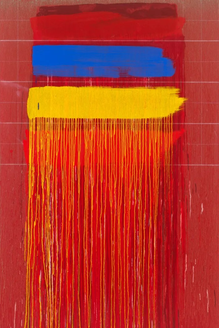 An abstract painting features three blocks of colour at the top of the canvas — red, blue, yellow — with vertical strips and drips of red and yellow painting running down the canvas