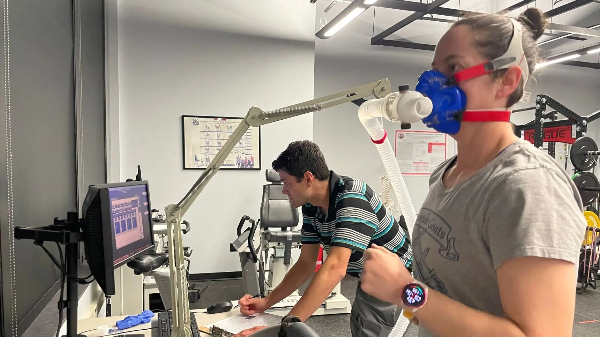 Beth on the treadmill with a mask, Dr. Wisniewski in the background